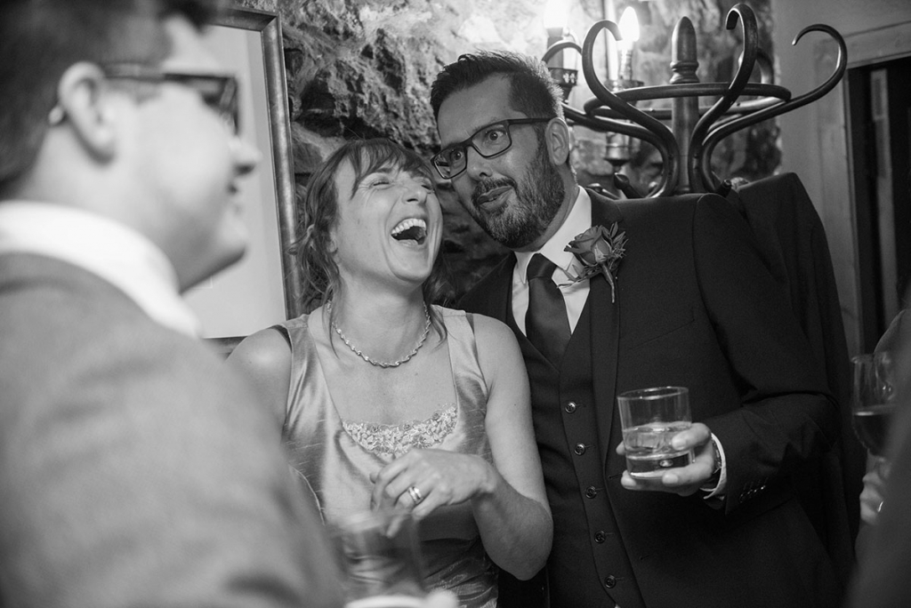 Candid photo of a man and woman in a bar at a wedding, having a drink and laughing