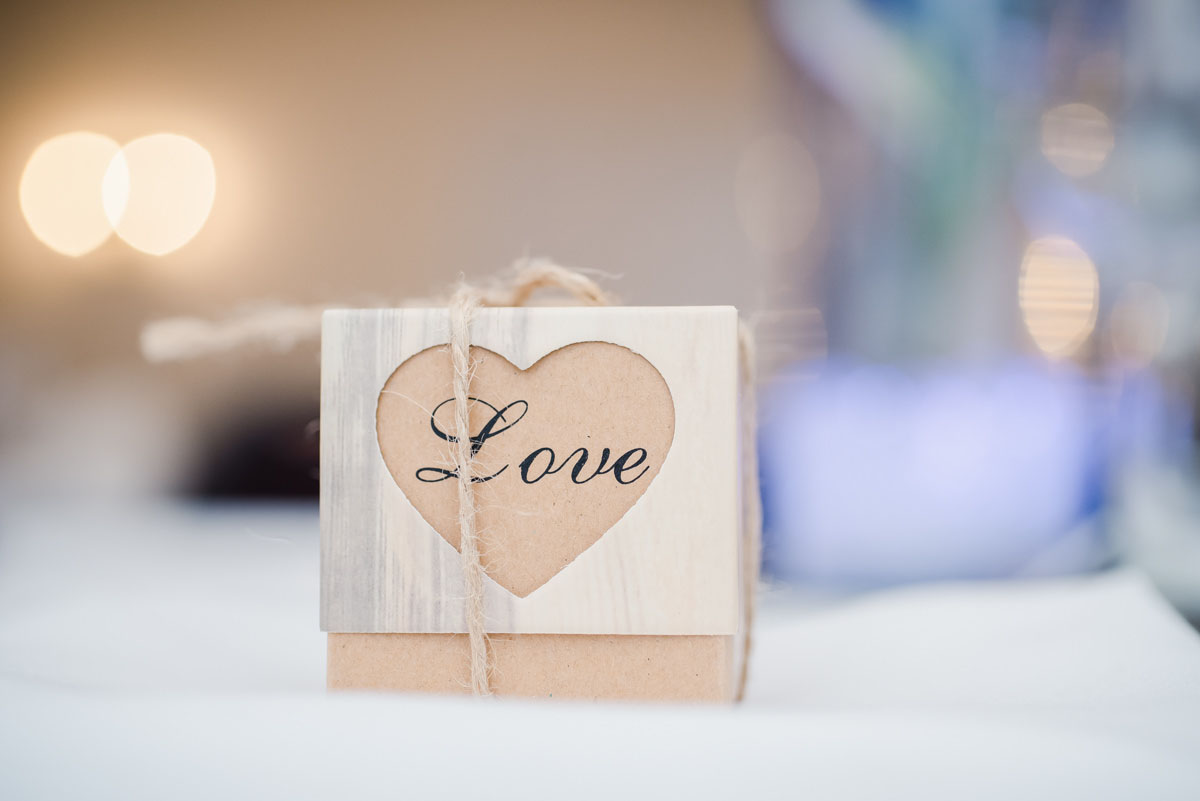 Wedding favour box with text that says 'love' enclosed within a heart shape and tied with string, on a table